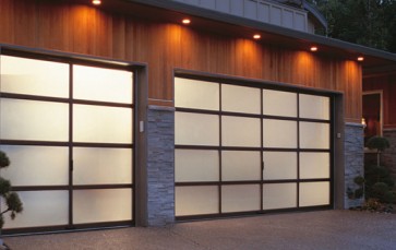 Two illuminated glass-panel garage doors at dusk